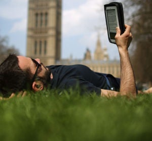 Un lector tumbado leyendo un libro electrónico Un lector tumbado leyendo un libro electrónico