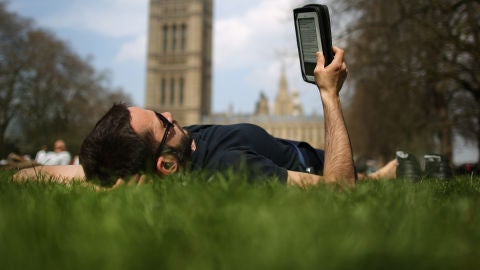 Un lector tumbado leyendo un libro electr&oacute;nico