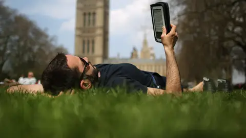 Un lector tumbado leyendo un libro electrónico Un lector tumbado leyendo un libro electrónico
