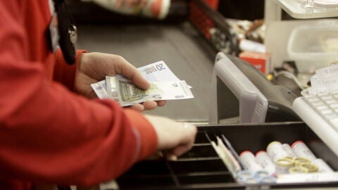 Una cajera de un supermercado devuelve el cambio a un cliente