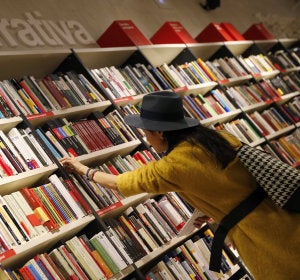 Una mujer mira libros en los estanterías de una librería Una mujer mira libros en los estanterías de una librería