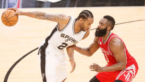 Kawhi Leonard sostiene el bal&oacute;n con una mano ante la defensa de James Harden