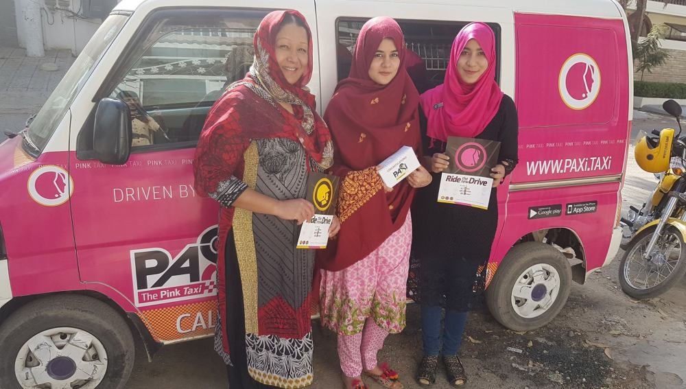 Tres mujeres pakistaníes posan junto a uno de los taxis rosas que circulan para proteger a las mujeres del acoso