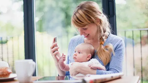 Una madre con su bebé mirando un smartphone Una madre con su bebé mirando un smartphone