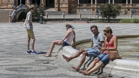 Turistas se refrescan en la plaza de España en Sevilla