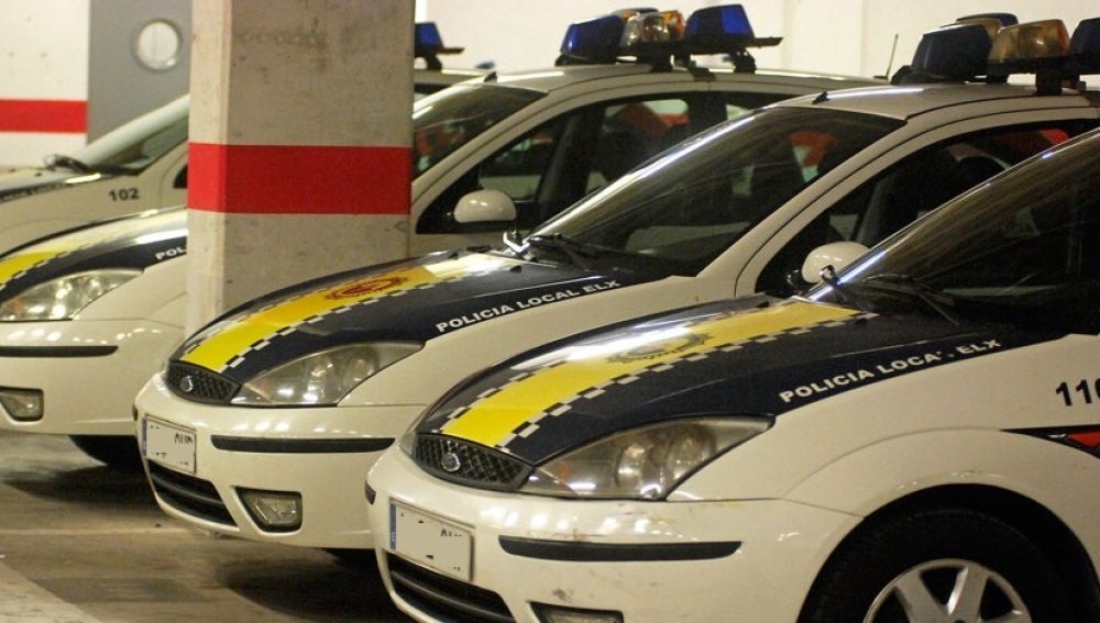 Vehículos de la Policía Local de Elche estacionados en el aparcamiento de la Jefatura. 