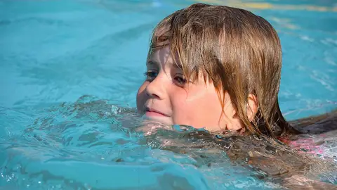 Una niña nada en una piscina Una niña nada en una piscina