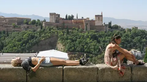 Unos turistas descansan y toman el sol en Granada. Unos turistas descansan y toman el sol en Granada.