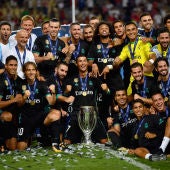 Los jugadores del Real Madrid se sientan sobre el césped con la Supercopa de Europa
