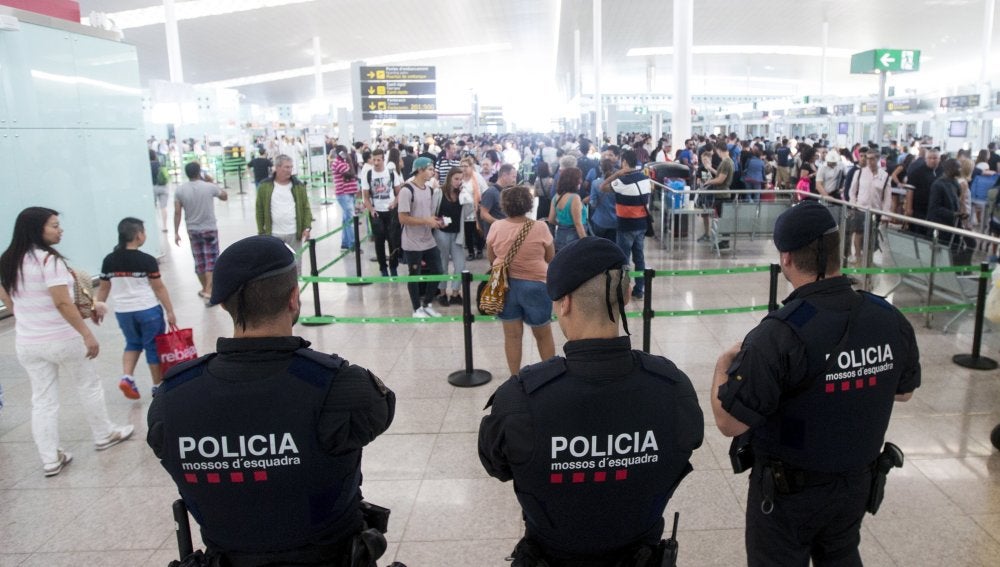 Agentes de los Mossos d'Esquadra controlan de los accesos a las puertas de embarque en el Aeropuerto de El Prat