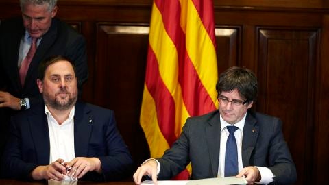 El presidente de la Generalitat, Carles Puigdemont, acompa&ntilde;ado por el vicepresidente Oriol Junqueras, firma la convocatoria de refer&eacute;ndum en el Parlament