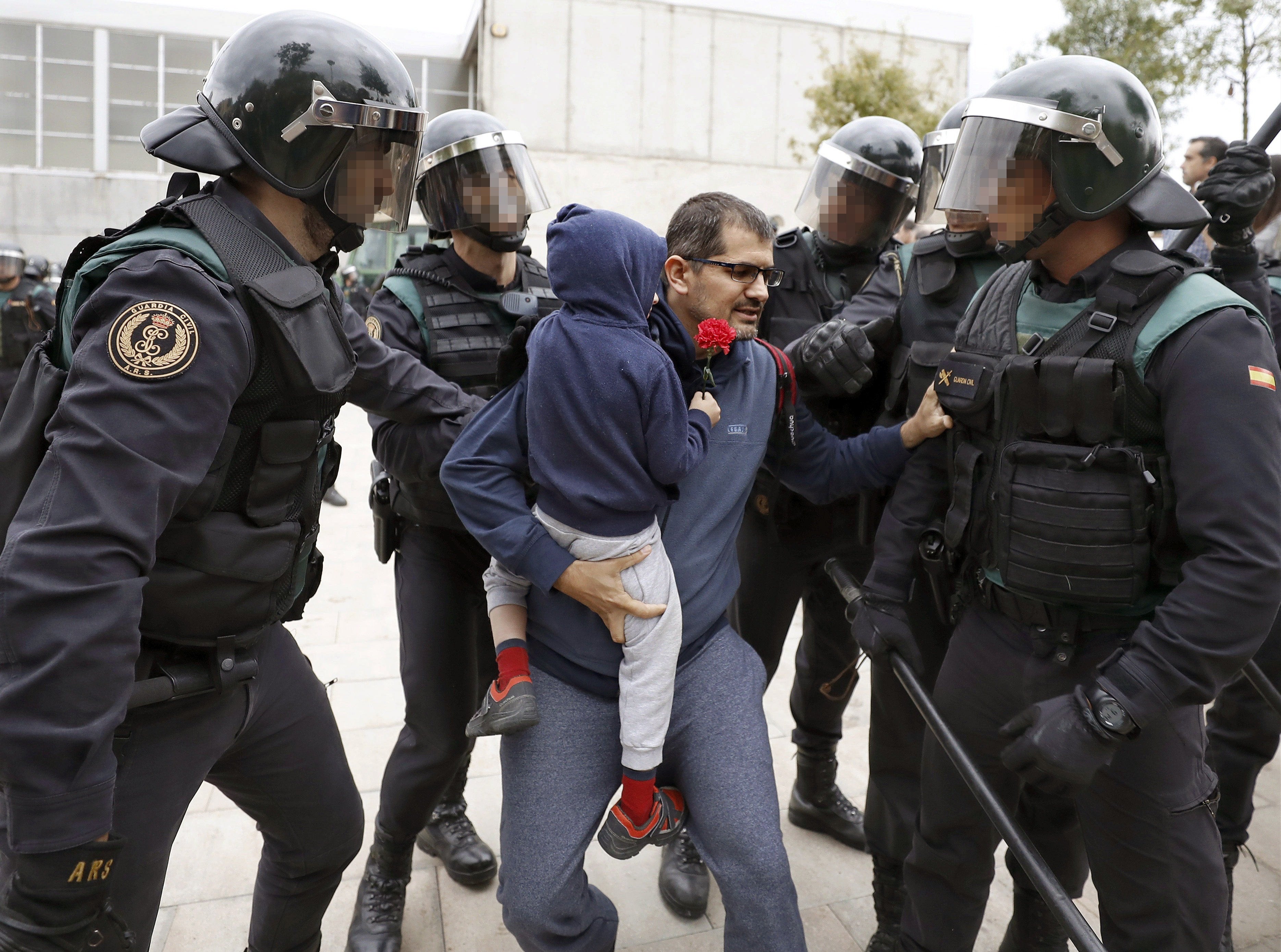 Una de las imágenes del 1-O: Un policía ayuda a un padre que lleva a su hijo a hombros Una de las imágenes del 1-O: Un policía ayuda a un padre que lleva a su hijo a hombros