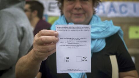 Una mujer muestra una papeleta del refer&eacute;ndum del 1-O 