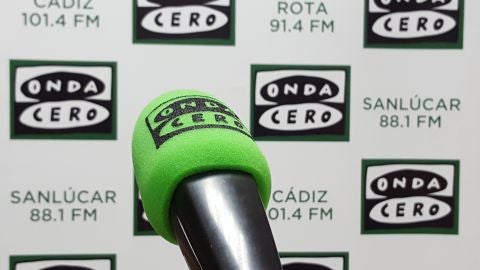 Micr&oacute;fono de presentador en los estudios de Onda Cero en C&aacute;diz. De fondo roll up de C&aacute;diz y Rota.