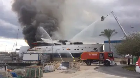 Continúan las tareas de extinción del aparatoso incendio de un yate en dique seco en la zona portuaria de Alicante Continúan las tareas de extinción del aparatoso incendio de un yate en dique seco en la zona portuaria de Alicante