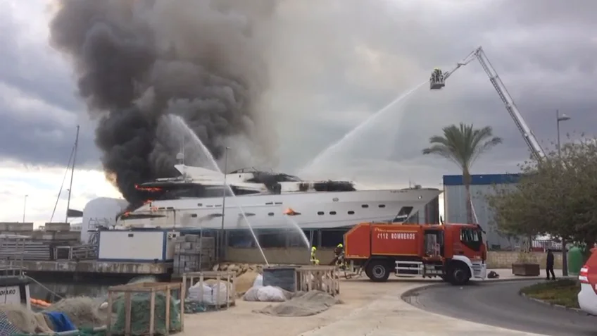 Continúan las tareas de extinción del aparatoso incendio de un yate en dique seco en la zona portuaria de Alicante Continúan las tareas de extinción del aparatoso incendio de un yate en dique seco en la zona portuaria de Alicante