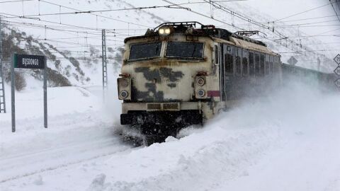 Un tren transita entre la nieve en la estaci&oacute;n de ferrocarril de Busdongo, en las proximidades del puerto de Pajares,