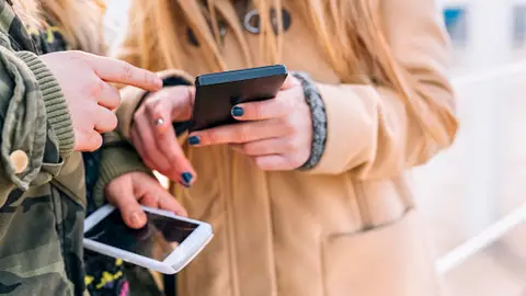Imagen de archivo de dos jóvenes mirando sus móviles Imagen de archivo de dos jóvenes mirando sus móviles
