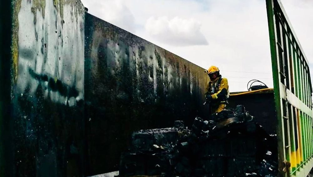 Un bombero en las labores de extinción de las llamadas el camión de reciclaje