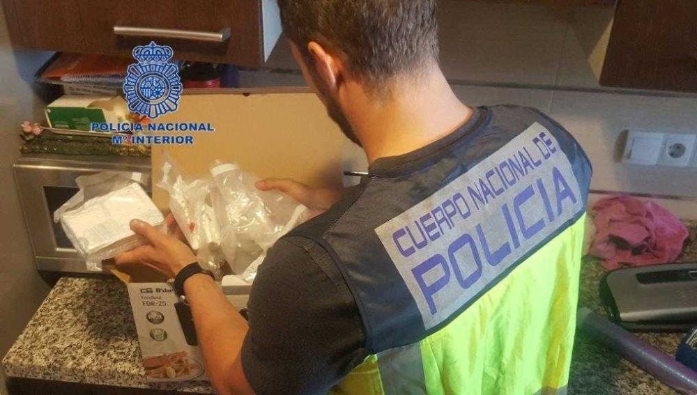Un agente de la Policía Nacional junto a parte de la cocaína incautada en Elche