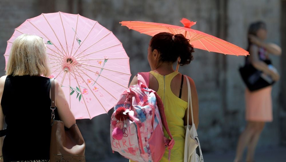 Dos mujeres se protegen del calor con unas sombrillas