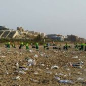 Operarios del servicio de limpieza recogen la basura acumulada en la playa El Carabassí de Elche después de la noche de San Juan.