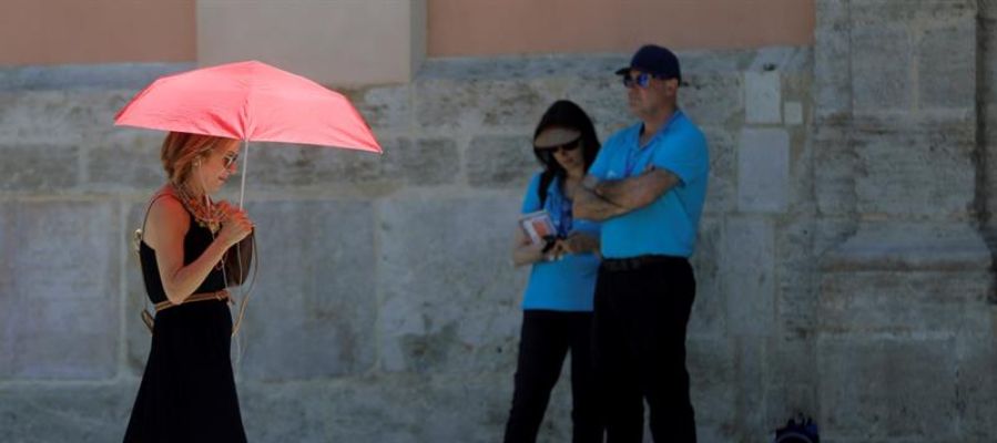 Una mujer se protege del calor con un paraguas Una mujer se protege del calor con un paraguas