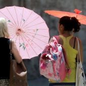 Imagen de archivo de dos mujeres protegiéndose del calor con unas sombrillas