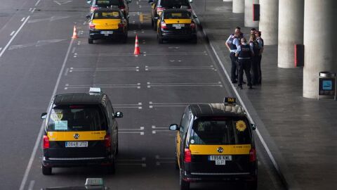 Un grupo de taxistas permanecen parados con sus veh&iacute;culos en el Aeropuerto de Barcelona
