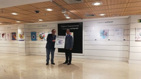 El Dr. Soler y el director de El Corte Ingl&eacute;s de Elche posan junto al cartel ganador