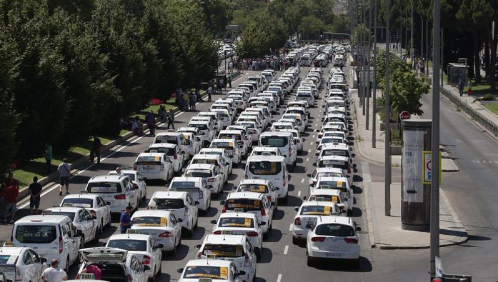 Un grupo de taxis permanecen concentrados a su paso por el ministerio de Fomento