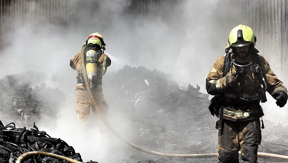 Bomberos apagando las llamas del incendio en el polígono industrial de Carrús de Elche
