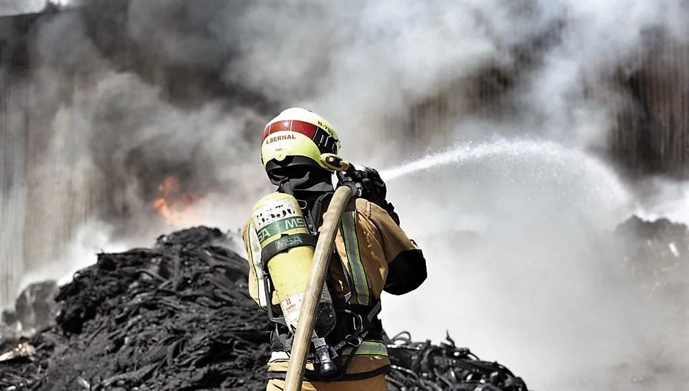 Un bombero en las labores de extinción del incendio originado en el polígono de Carrús de Elche