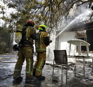 Dos bomberos refrescan el interior de una de las viviendas afectadas por el incendio forestal de Llutxent Dos bomberos refrescan el interior de una de las viviendas afectadas por el incendio forestal de Llutxent