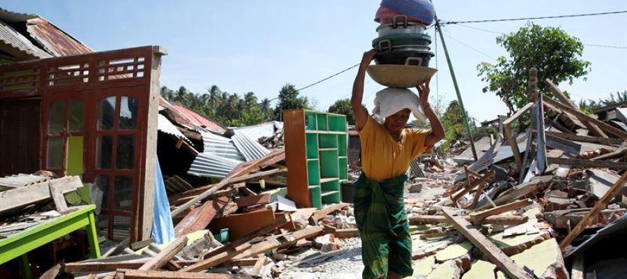 Una mujer carga con sus pertenencias entre los escombros en Lombok (Indonesia) tras el terremoto Una mujer carga con sus pertenencias entre los escombros en Lombok (Indonesia) tras el terremoto