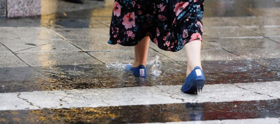 Una mujer cruza por un paso de peatones bajo una fuerte tormenta (Archivo) Una mujer cruza por un paso de peatones bajo una fuerte tormenta (Archivo)