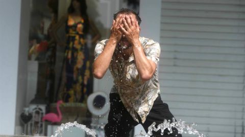 Un hombre intenta refrescarse en una fuente 