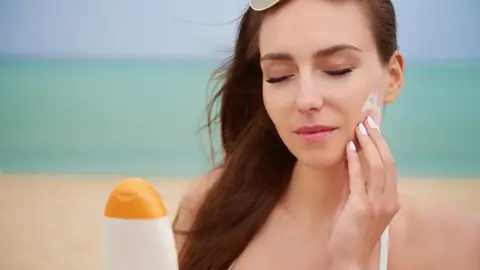 Mujer poniendo crema solar en la cara Mujer poniendo crema solar en la cara