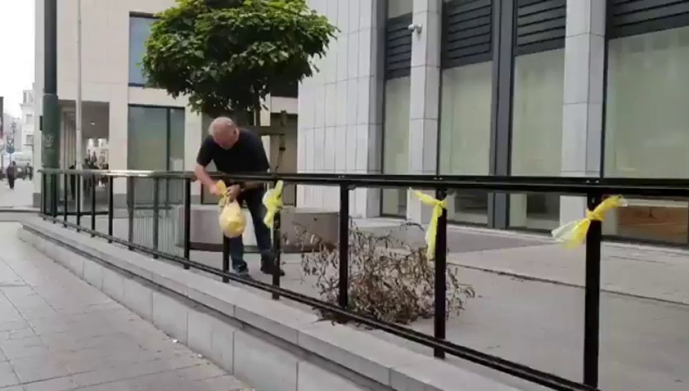 Un operario retira varios lazos amarillos colocados a la entrada del Tribunal belga antes de la vista sobre Llarena