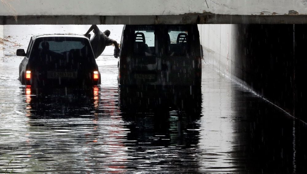 Una persona intenta sale de una furgoneta atrapada en un tunel de Alfafar debido a las intensa lluvias