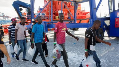 Varios inmigrantes salen de la embarcac&iacute;on para subir a un autob&uacute;s que los llevar&aacute; a San Roque
