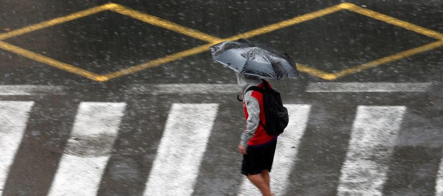 Una persona se protege de la lluvia con un paraguas Una persona se protege de la lluvia con un paraguas