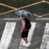 Una persona se protege de la lluvia con un paraguas. Una persona se protege de la lluvia con un paraguas.