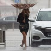 Una mujer sujeta el paraguas intentando que no se le vuele debido al viento