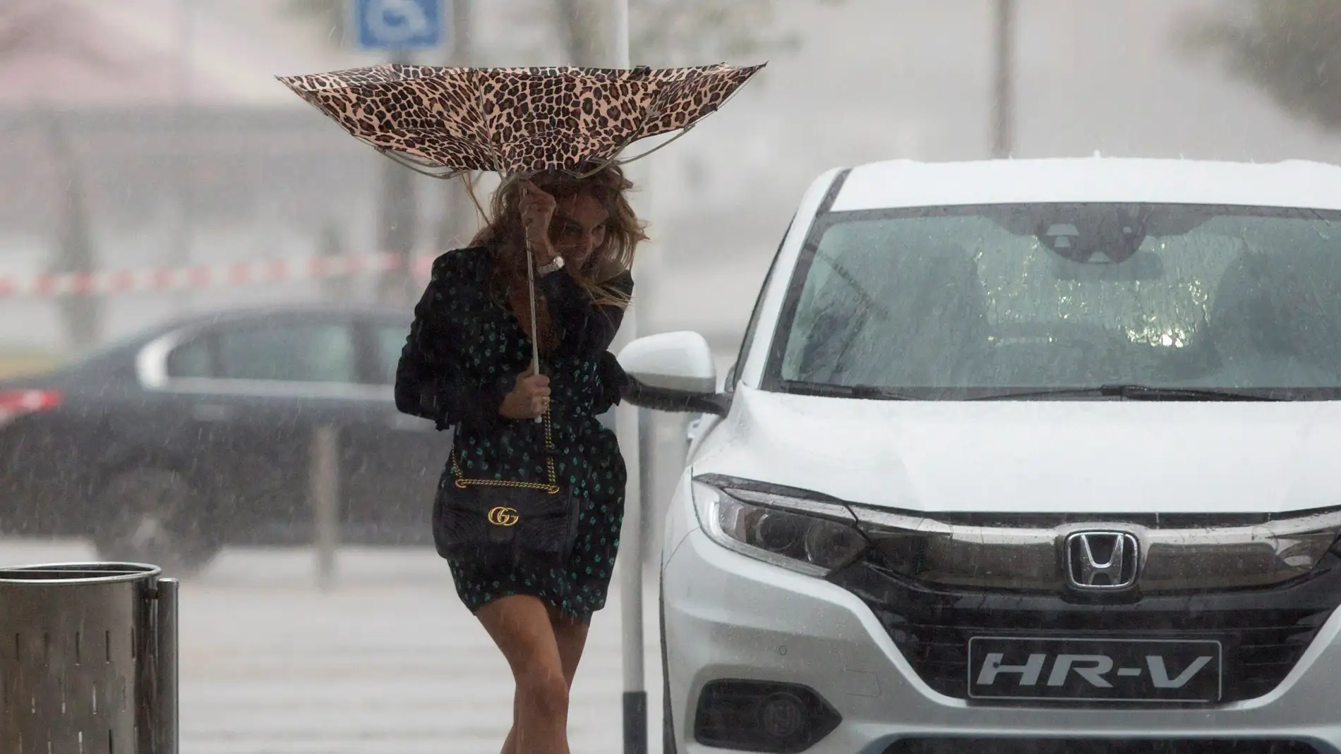 Una mujer sujeta el paraguas intentando que no se le vuele debido al viento