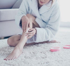 Mujer aplicando crema en las piernas Mujer aplicando crema en las piernas