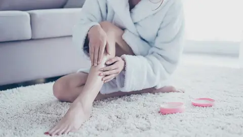 Mujer aplicando crema en las piernas Mujer aplicando crema en las piernas