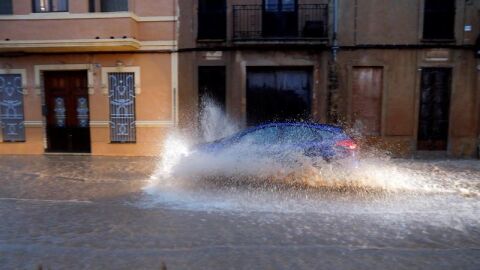 Un veh&iacute;culo circula por una calle anegada de Valencia