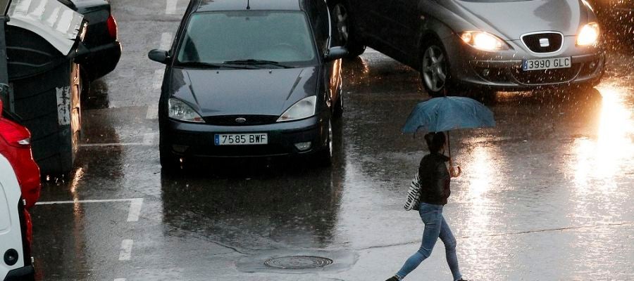 Imagen de una persona que se protege con un paraguas de la lluvia Imagen de una persona que se protege con un paraguas de la lluvia