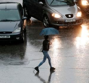 Imagen de una persona que se protege con un paraguas de la lluvia Imagen de una persona que se protege con un paraguas de la lluvia